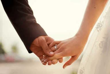Zwei Hände von einem Brautpaar welche sich halten, an einer Hand der Ring sichtbar.